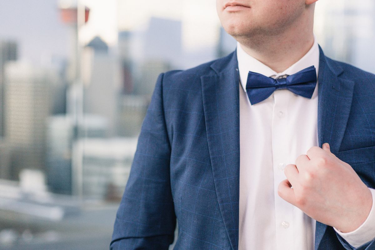 A close detail of the groom's navy jacket and bow tie