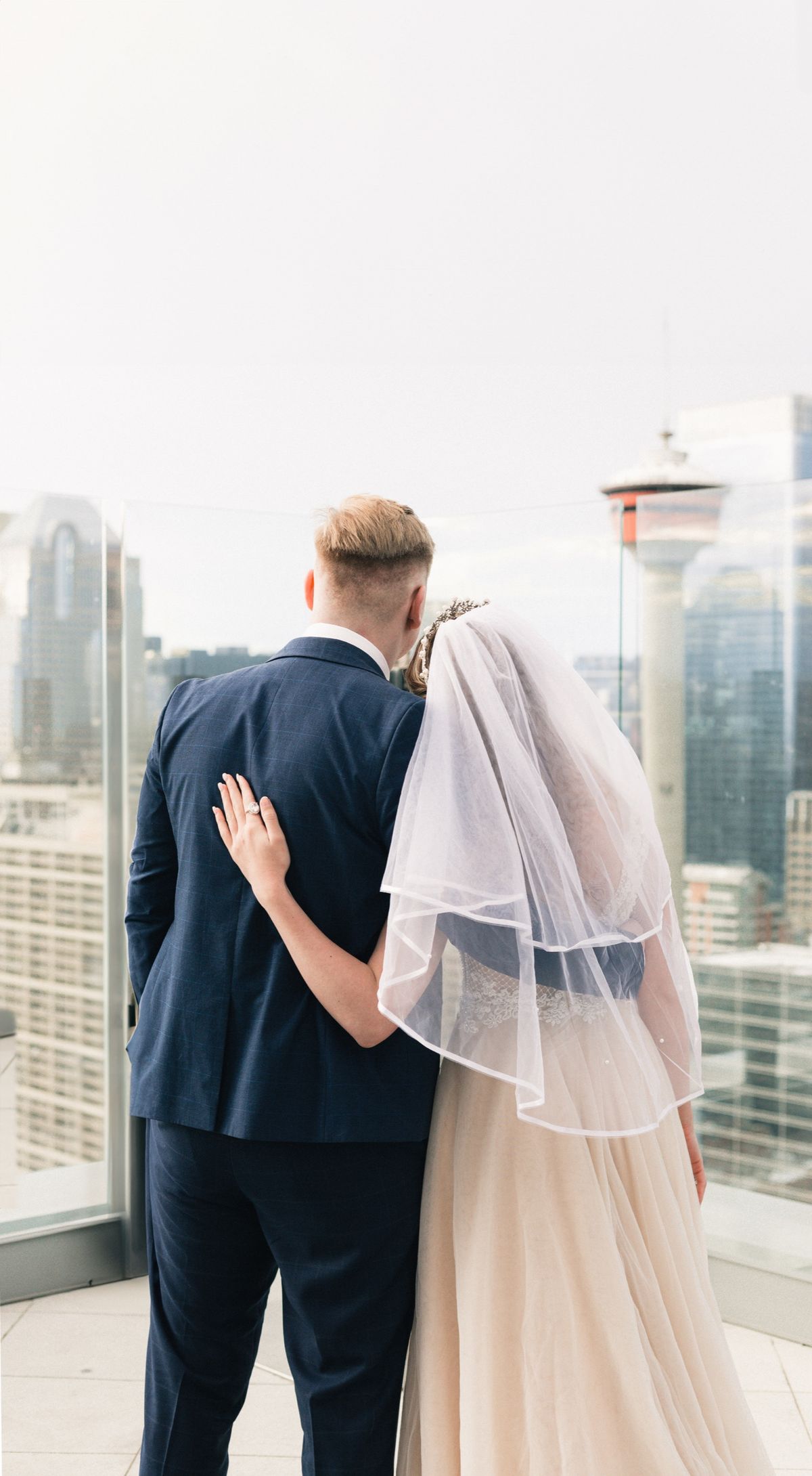 The bride and groom from behind, looking out at the Calgary Tower
